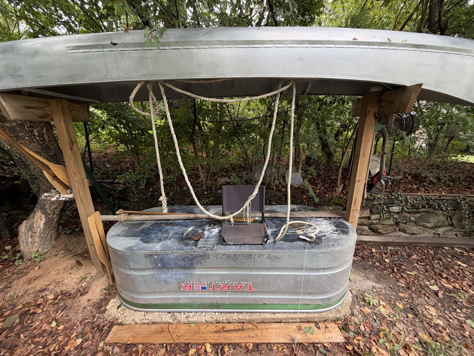 The workbench on the stock tank under the upturned canoe, rope, knife and camp seat