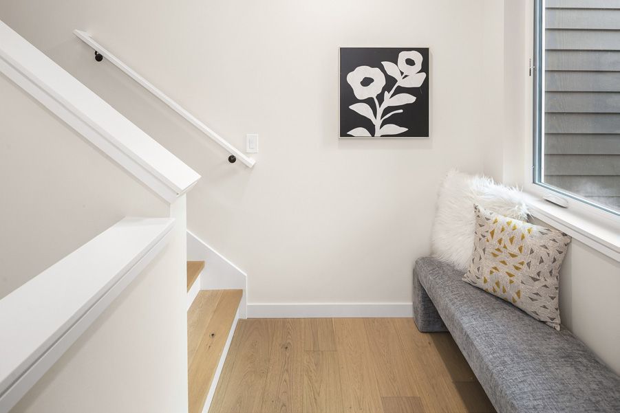 Stair landing with a grey cushioned bench under a window