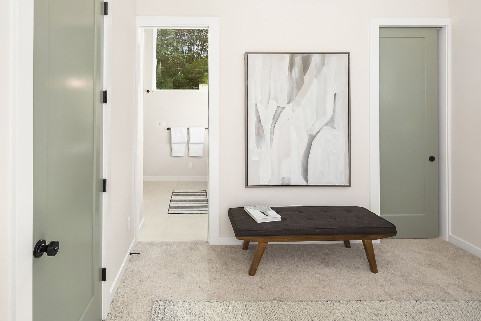 Primary suite with two matching sage doors flanking a bench and artwork