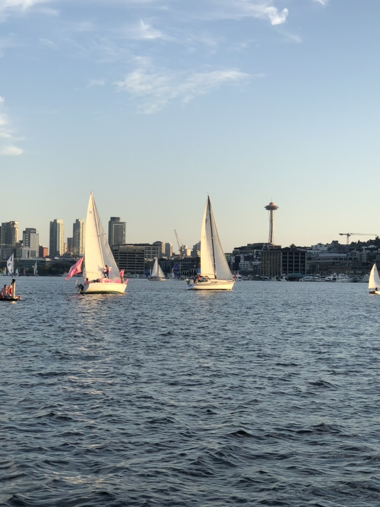 Sailboats racing on Lake Union with the Seattle skyline and the Space Needle behind them.