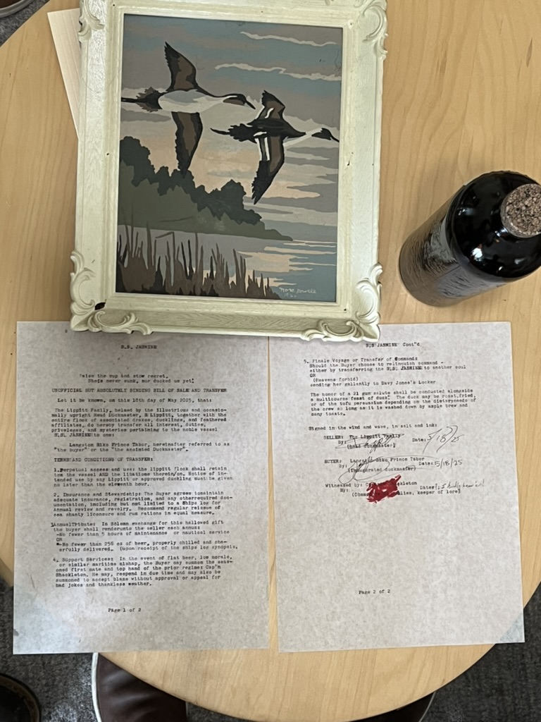 Overhead view of the signed contract pages laid out with a photograph and a bottle of grog.