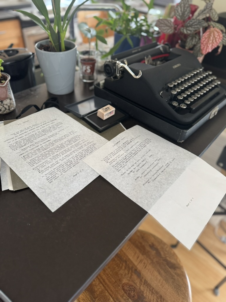 The two-page Jasmine transfer document on a table beside a black Corona typewriter, a wooden stamp and an open ink pad.
